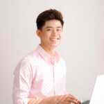 Smiling student at laptop wearing a pink shirt